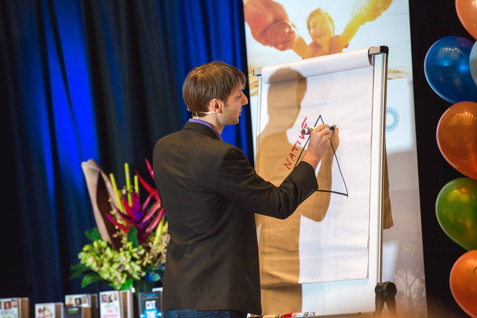 Carl Taylor teaching on stage with a flip chart and marker